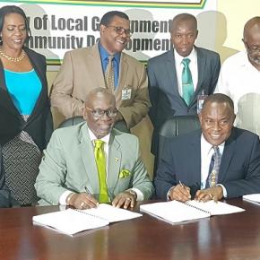 L-R front row: Hugh Burton, HDB Construction Ltd., HM McKenzie, Portmore Mayor Leon Thomas, CEO, Portmore MC, Kerry Chambers. Mp for Southern St. Catherine Fitz Jackson (extreme right) observes the signing